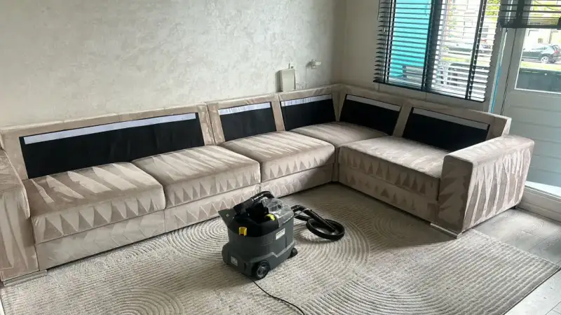 Beige hoekbank met vloerkleed in een woonkamer na de behandeling