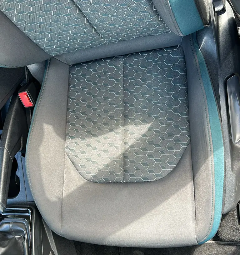 Voorstoel van een auto met stoffen bekleding na de reiniging, gezien door het open portier