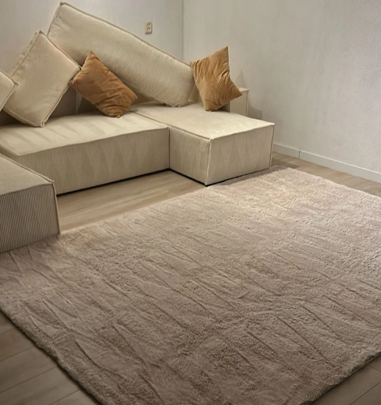 Licht hoogpolig vloerkleed voor een witte bank, na de reiniging